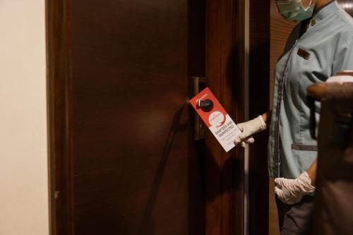 a person wearing a mask is unlocking a door at Swiss-Belhotel Serpong in Serpong