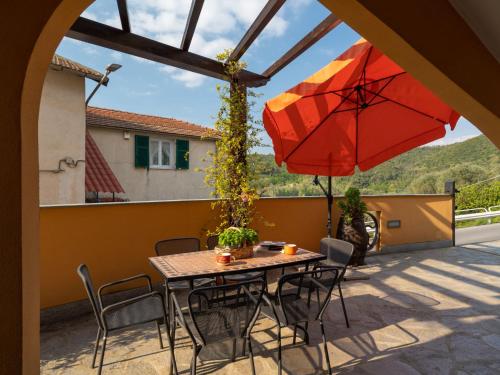 einen Tisch, Stühle und einen Regenschirm auf einer Terrasse in der Unterkunft Apartment A' Ca' de Alida by Interhome in Ortovero