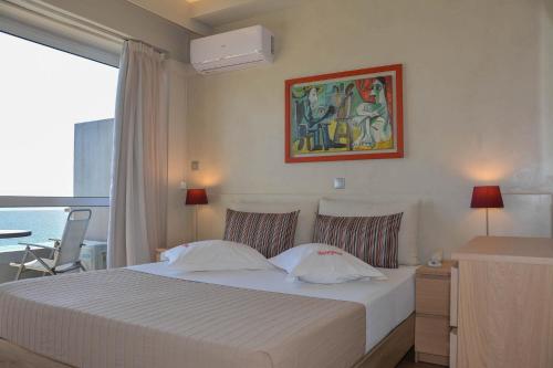 a bedroom with a white bed with a painting on the wall at Scorpios Sea Side Hotel in Piraeus