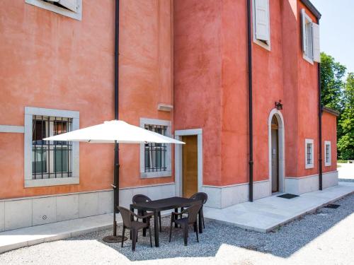 stół i krzesła z parasolem przed budynkiem w obiekcie Apartment Winery Villa Vitas - App-3 by Interhome w mieście Strassoldo