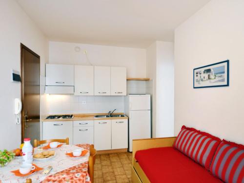 eine kleine Küche mit einem Tisch und einem roten Sofa in der Unterkunft Apartment Pleione-1 by Interhome in Bibione