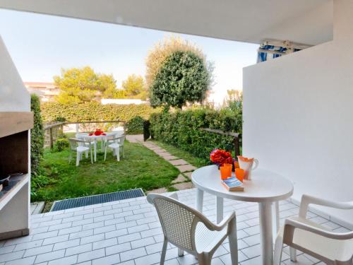 un patio con mesa y sillas y un jardín en Holiday Home Villaggio Maja by Interhome, en Bibione