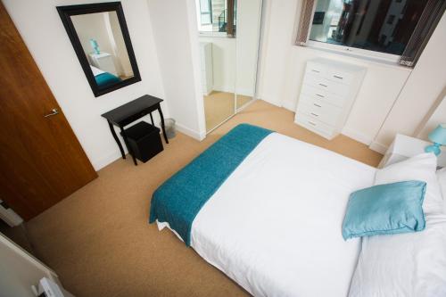 Schlafzimmer mit einem weißen Bett und einem Spiegel in der Unterkunft Meridian Tower Apartment in Swansea