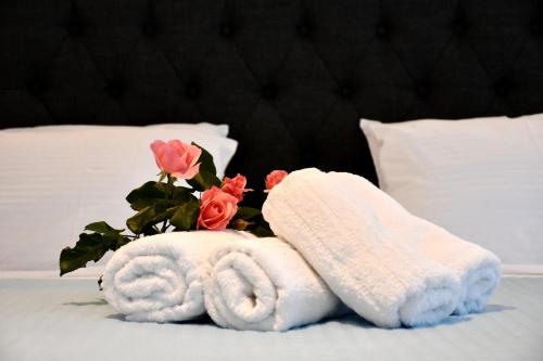 a bed with two towels and a bouquet of roses at The Blue Rooms in Áyioi Apóstoloi