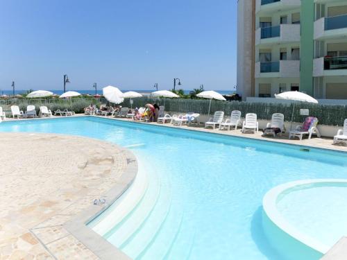 a large swimming pool with chairs and umbrellas at Apartment Casa del Mar-2 by Interhome in Roseto degli Abruzzi