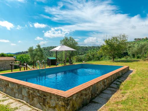 a swimming pool with a stone wall and an umbrella at Holiday Home Valmarinella by Interhome in Ravi