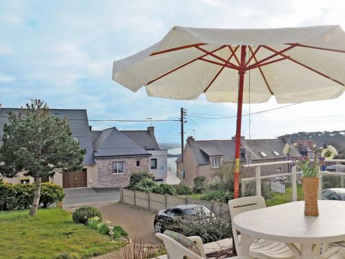 a white table with a white umbrella in a yard at Holiday Home Etoile de Mer by Interhome in Erquy