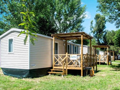 a white tiny house with a porch on the grass at Holiday Home Residence Village-1 by Interhome in Cavallino-Treporti