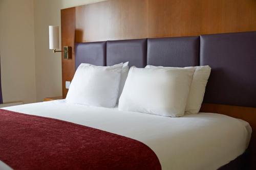1 cama con almohadas blancas en una habitación de hotel en Crossroads by Chef & Brewer Collection en Weedon Bec