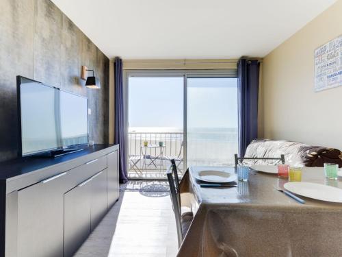 a living room with a television and a table with a view at Apartment Les Romarins by Interhome in Narbonne-Plage