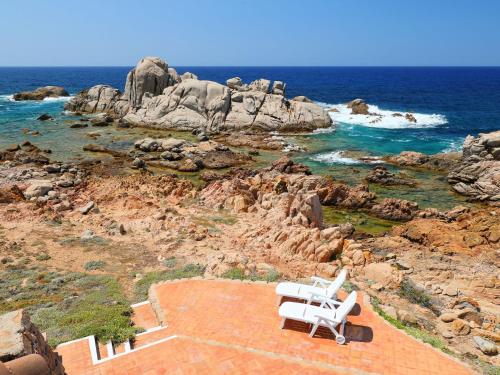 una sedia bianca seduta sulla cima di una spiaggia rocciosa di Holiday Home La Cala - VGM615 by Interhome a Aglientu