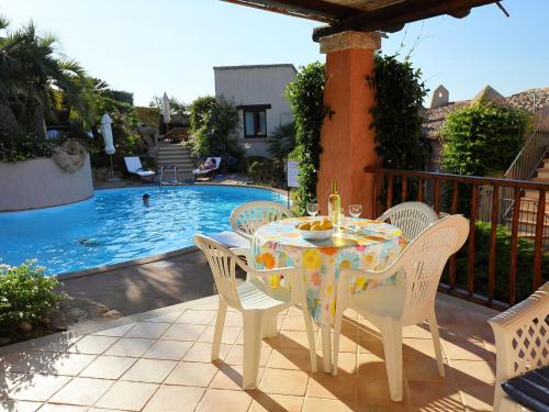 a table and chairs on a patio next to a pool at Holiday Home Erica 22 - Vista Village by Interhome in Porto San Paolo