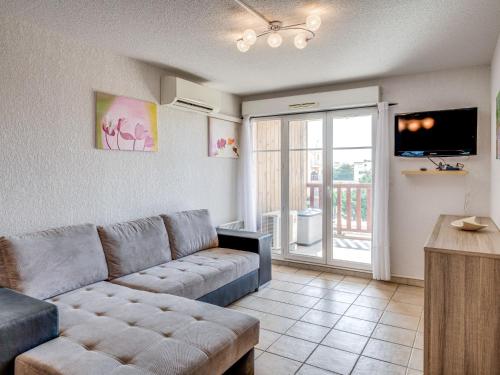 un salon avec un canapé et une porte coulissante en verre dans l'établissement Apartment Les Grandes Bleues 2-5 by Interhome, à Narbonne-Plage
