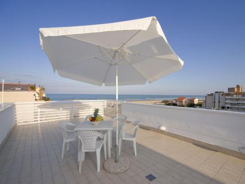a white table and chairs with an umbrella on a balcony at Apartment Rosburgo-4 by Interhome in Roseto degli Abruzzi