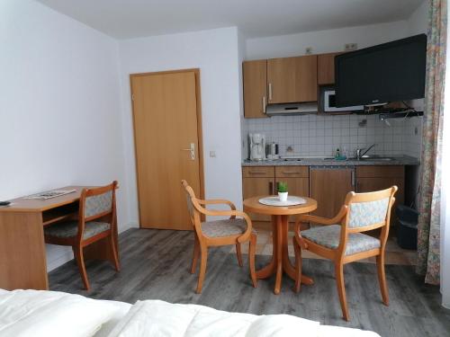 a room with a table and chairs and a kitchen at Pension Landidylle in Wohlenhagen