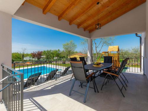 un patio con mesa, sillas y piscina en Holiday Home Villa Veli vrt by Interhome en Žminj