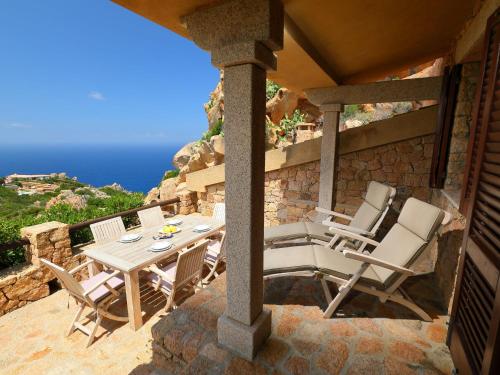 um pátio com uma mesa e cadeiras e o oceano em Holiday Home Il Nido by Interhome em Li Valcaggi