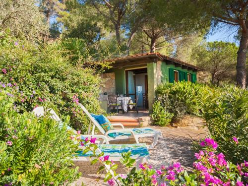 ein grünes Haus mit 2 Stühlen und einem Tisch in der Unterkunft Holiday Home Piccola Oasi-5 by Interhome in Capoliveri