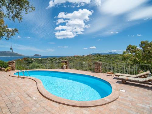 a swimming pool on a brick patio with a view of the water at Holiday Home Gardenia by Interhome in Pittulongu