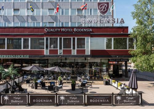 a hotel with tables and umbrellas in front of a building at Quality Hotel Bodensia in Boden