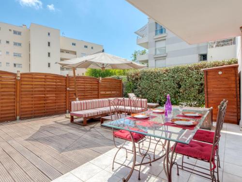 un patio avec une table, des chaises et un parasol dans l'établissement Apartment Les allées du Cap-3 by Interhome, à Antibes