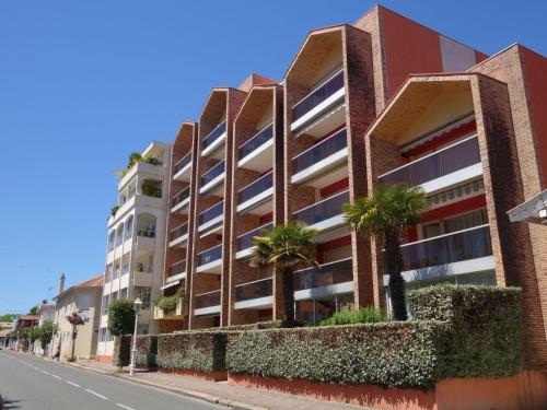 un bâtiment en briques rouges avec des arbres en façade d'une rue dans l'établissement Apartment Plein Soleil-2 by Interhome, à Arcachon