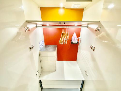 a kitchen with white cabinets and an orange wall at Èrsextius, GGB1, Aix-en-Provence in Aix-en-Provence