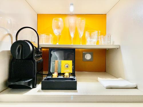 - une étagère avec des verres à vin et une cafetière dans l'établissement Èrsextius, GGB1, Aix-en-Provence, à Aix-en-Provence