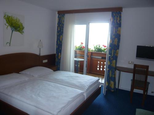 um quarto com uma cama, uma secretária e uma janela em Frühstückspension Seeblick em Sankt Gilgen