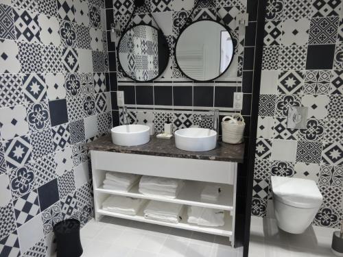 La salle de bains est pourvue d'un lavabo, d'un miroir et de carrelage. dans l'établissement Les Petites Tuileries, à Bray-sur-Seine