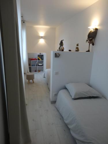 a bedroom with two beds and a white wall at Les Petites Tuileries in Bray-sur-Seine