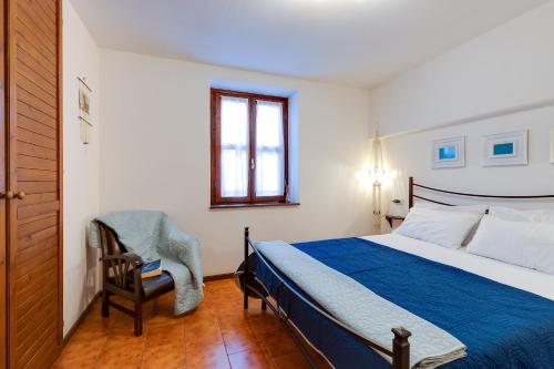 a bedroom with a bed and a chair and a window at Villa Viola in Narbolia
