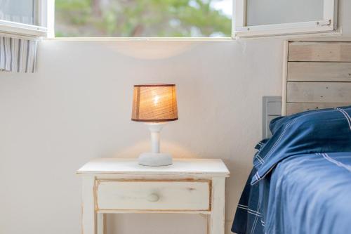 a lamp on a night stand next to a bed at Pregonda 13 Menorca in Son Parc