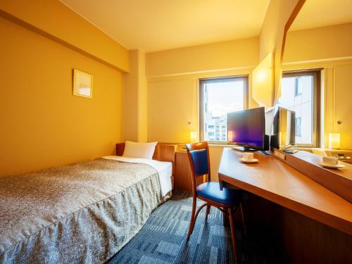 a hotel room with a bed and a desk with a computer at Hotel Ace Morioka in Morioka
