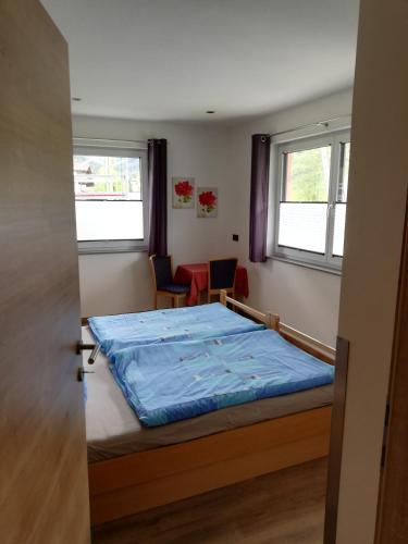 a small room with a bed and two windows at Haus Seppi in Neukirchen am Großvenediger