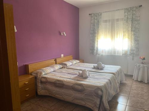 1 dormitorio con 2 camas y pared púrpura en Apartamentos alcala, en Ibdes
