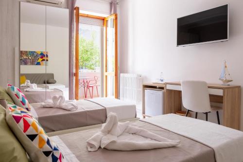a room with three beds and a desk and a television at Vele d'Otranto B&B in Otranto