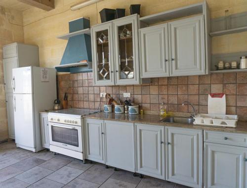 cocina con armarios blancos y nevera blanca en Ta' Lorenzo Farmhouse en San Lawrenz