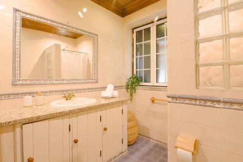 W łazience znajduje się umywalka i lustro. w obiekcie Quinta dos Manteiros com Piscina Coberta w mieście Póvoa de Santo António