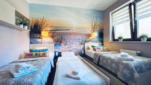 two beds in a room with a beach mural at Apartament Plaza 7 - Rezydencja Nadmorska Rogowo in Rogowo