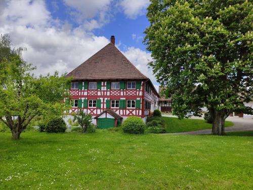 a red house with a green door in the grass at Hofgut Breitenbach in Markdorf
