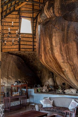 a living room with a large log wall at Big Cave Camp in Matopos
