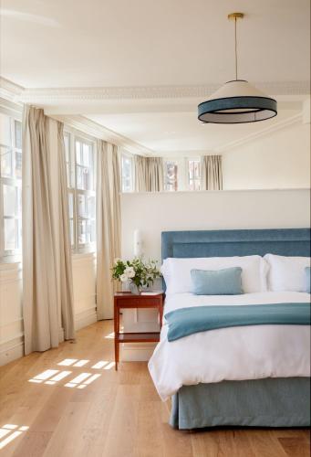 a bedroom with a blue bed and windows at Gran hotel Brillante in San Esteban de Pravia