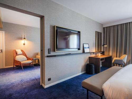 a hotel room with a bed and a flat screen tv at Crowne Plaza - Nice - Grand Arenas by IHG in Nice