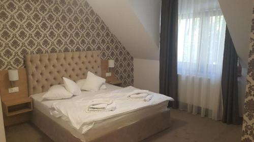 a bedroom with a bed with white sheets and a window at Vila Turistica Principesa Margareta in Beiuş