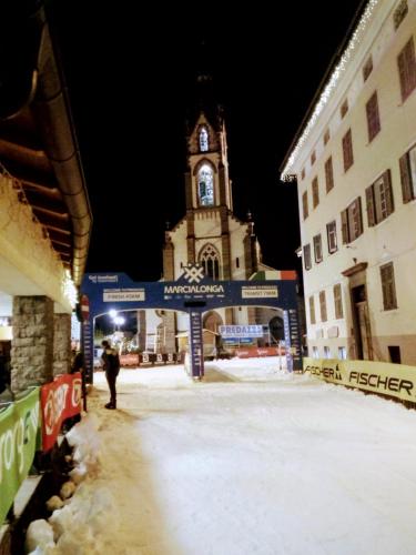a building with a clock tower in the snow at Le Bifore in valle in Predazzo