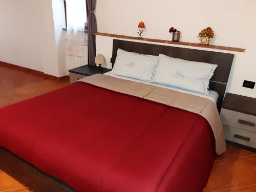 a bedroom with a large bed with a red blanket at La casa in giardino in Volterra