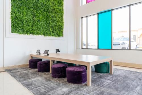 a table and purple stools in a room with a green wall at Dara Qurtubah Hotel in Riyadh