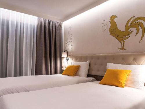 two beds in a hotel room with a chicken on the wall at ibis Styles Lublin Stare Miasto in Lublin