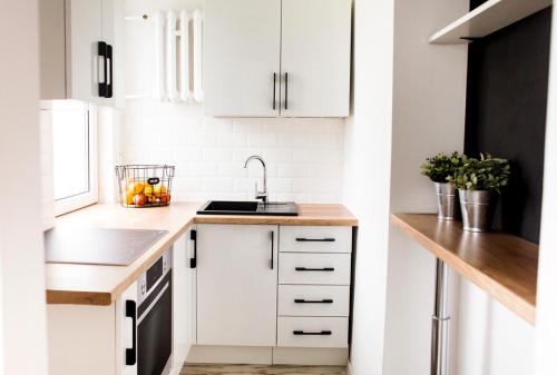 uma cozinha com armários brancos e um lavatório em Apartament Rycerski em Malbork